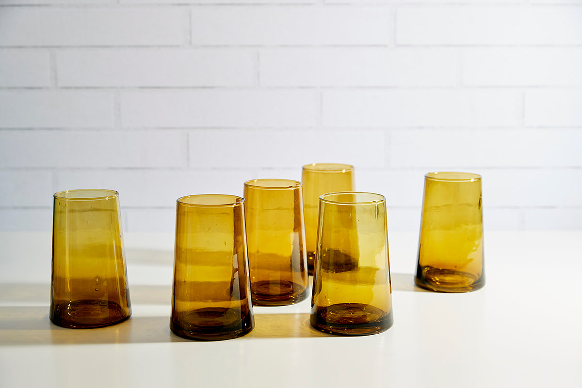 Six amber cone-shaped glasses with gradient coloring from dark brown base to light yellow top.