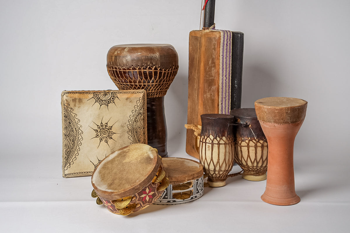 Collection of Moroccan percussion instruments including wooden drums, tambourine, and decorative fabric case.