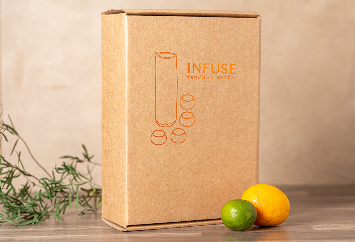 Kraft cardboard box labeled "INFUSE Tequila Mezcal" with infusion bottle illustration, displayed with citrus fruits and herbs