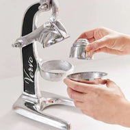 Silver and black lever citrus juicer with two stainless steel cone attachments held in hands during use.