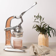 Manual citrus juicer with metal and wood construction, lever handle, and collection cup on base.