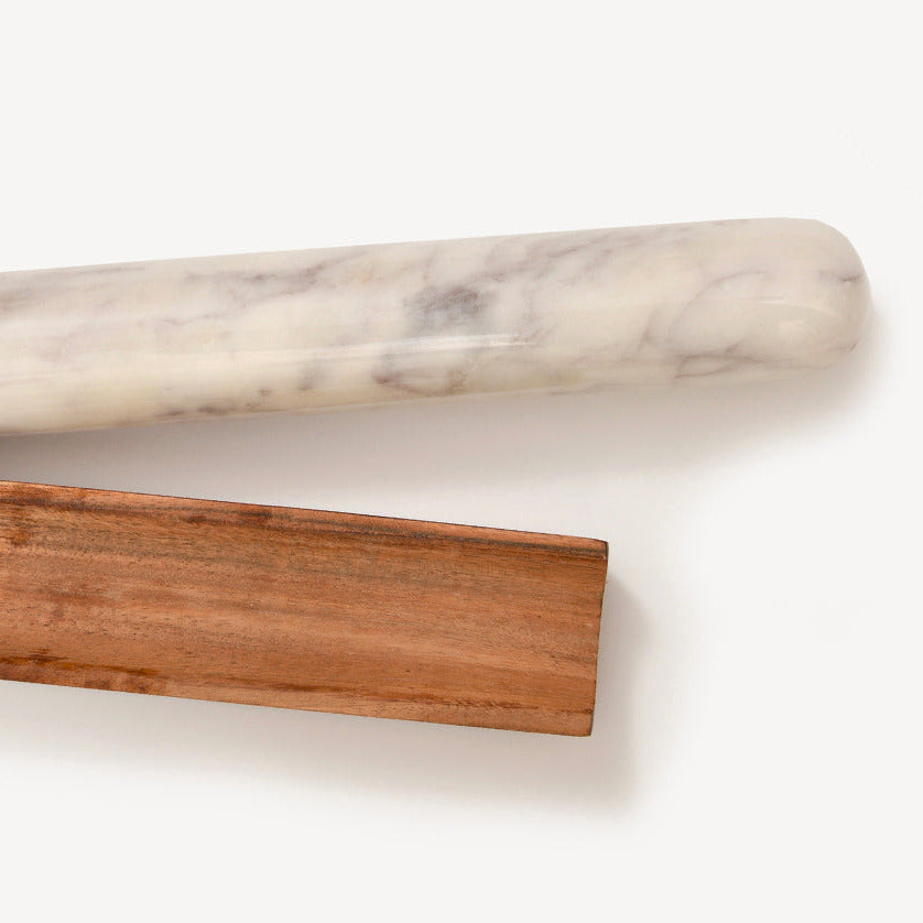 White marble rolling pin with gray veining and brown wooden rectangular base displayed separately.
