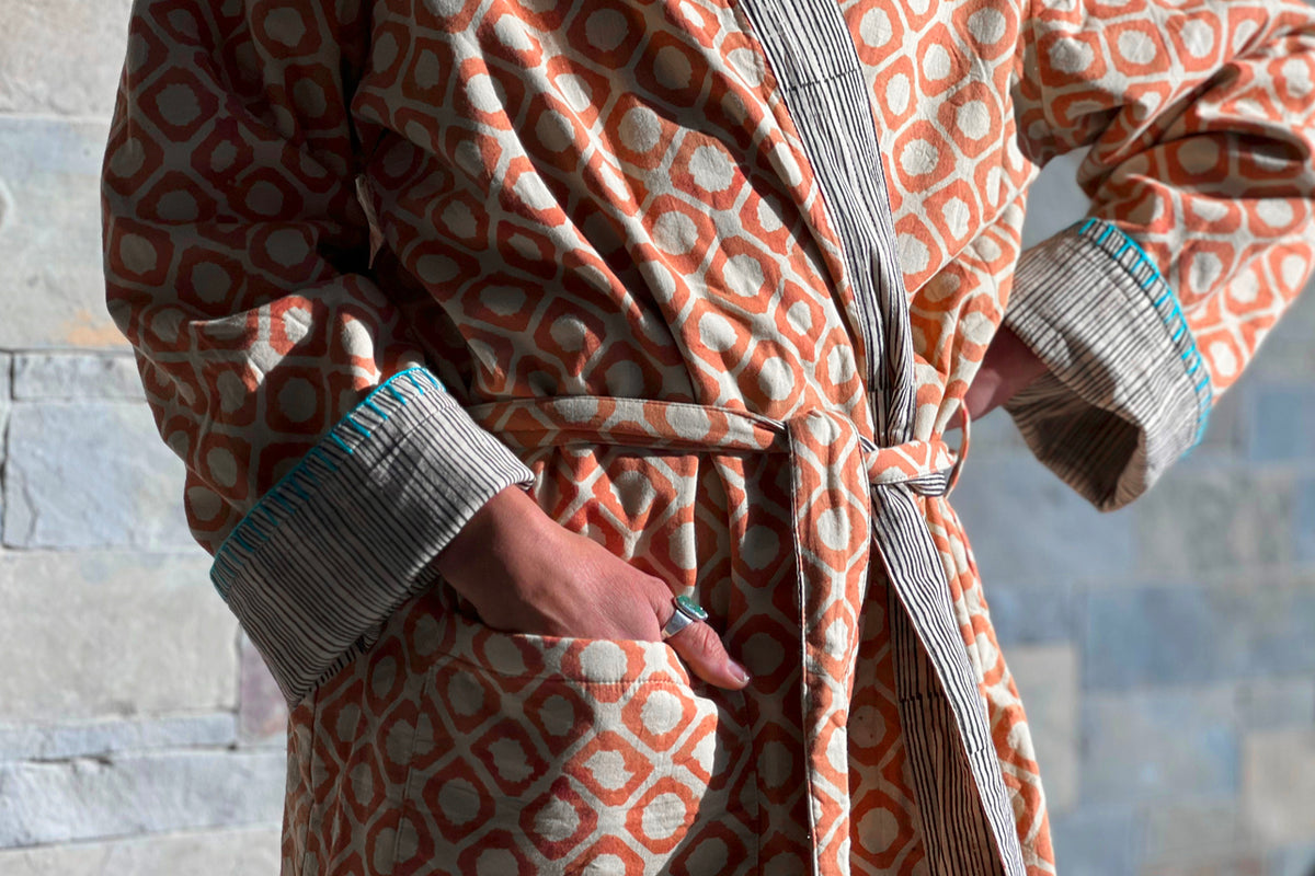 Rust and cream block print robe with striped cuffs and tie belt, worn open to show reversible side.