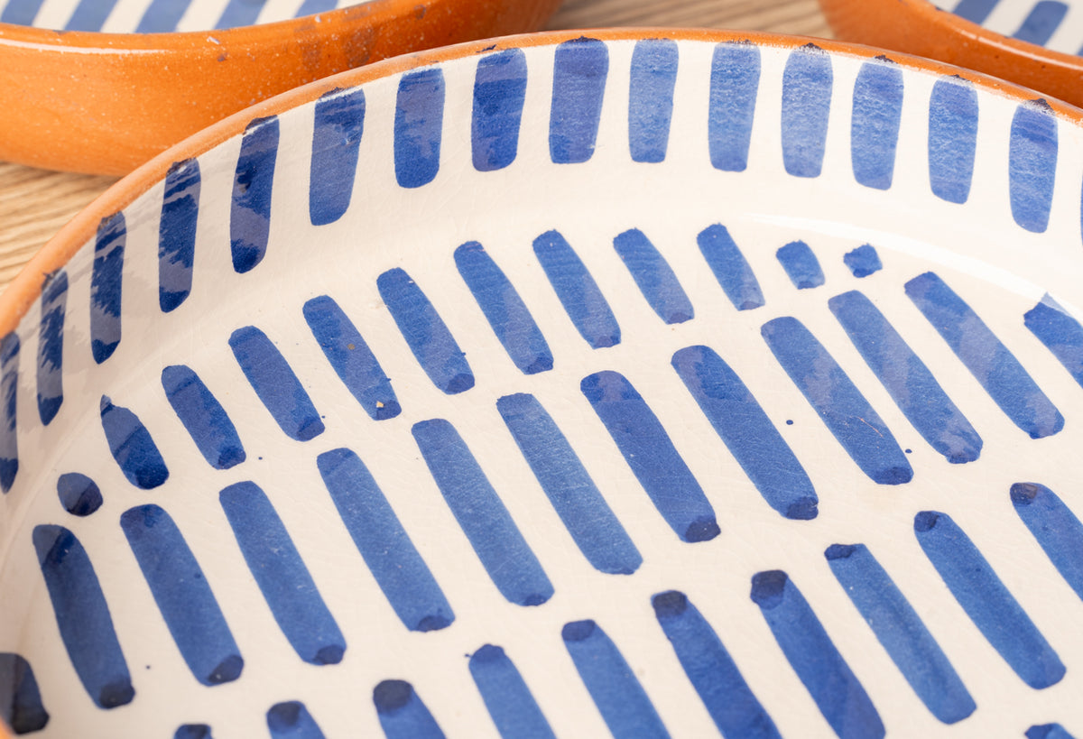 Ceramic nesting dishes with blue striped pattern and orange handles, shown stacked together.