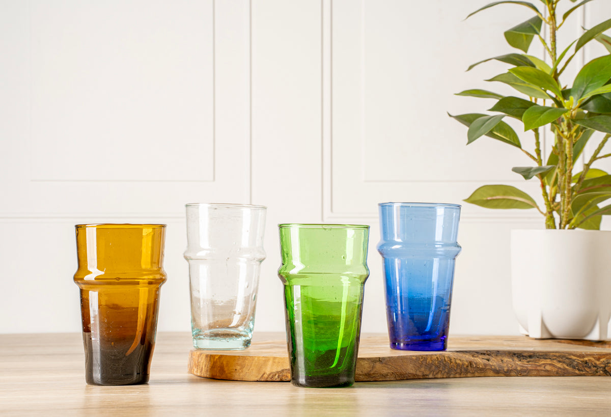 Six stacked glasses in amber, clear, green, and blue with textured band detail, displayed on wooden surface.