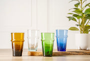 Six stacked glasses in amber, clear, green, and blue with textured band detail, displayed on wooden surface.