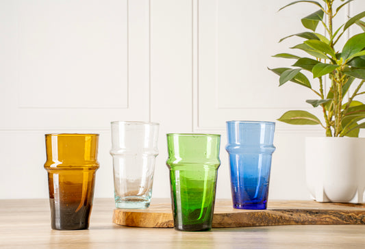 Six stacked glasses in amber, clear, green, and blue with textured band detail, displayed on wooden surface.