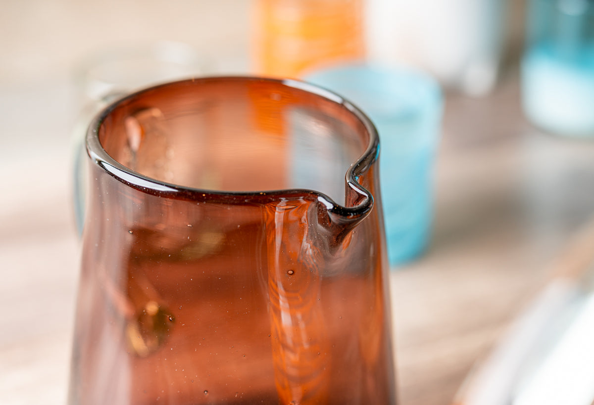 Amber glass pitcher with a curved spout, filled with brown liquid.