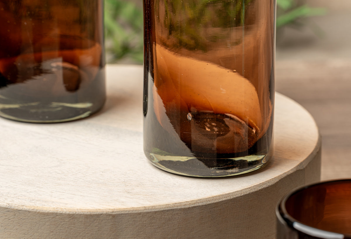 Four handblown glasses with tamarind-colored brown and amber gradient glass, displayed on a white ceramic surface.