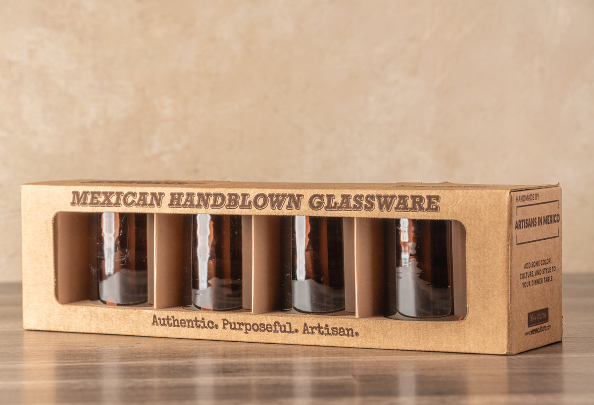 Set of four tamarind-colored handblown glasses with white striped detail visible through cardboard packaging window.