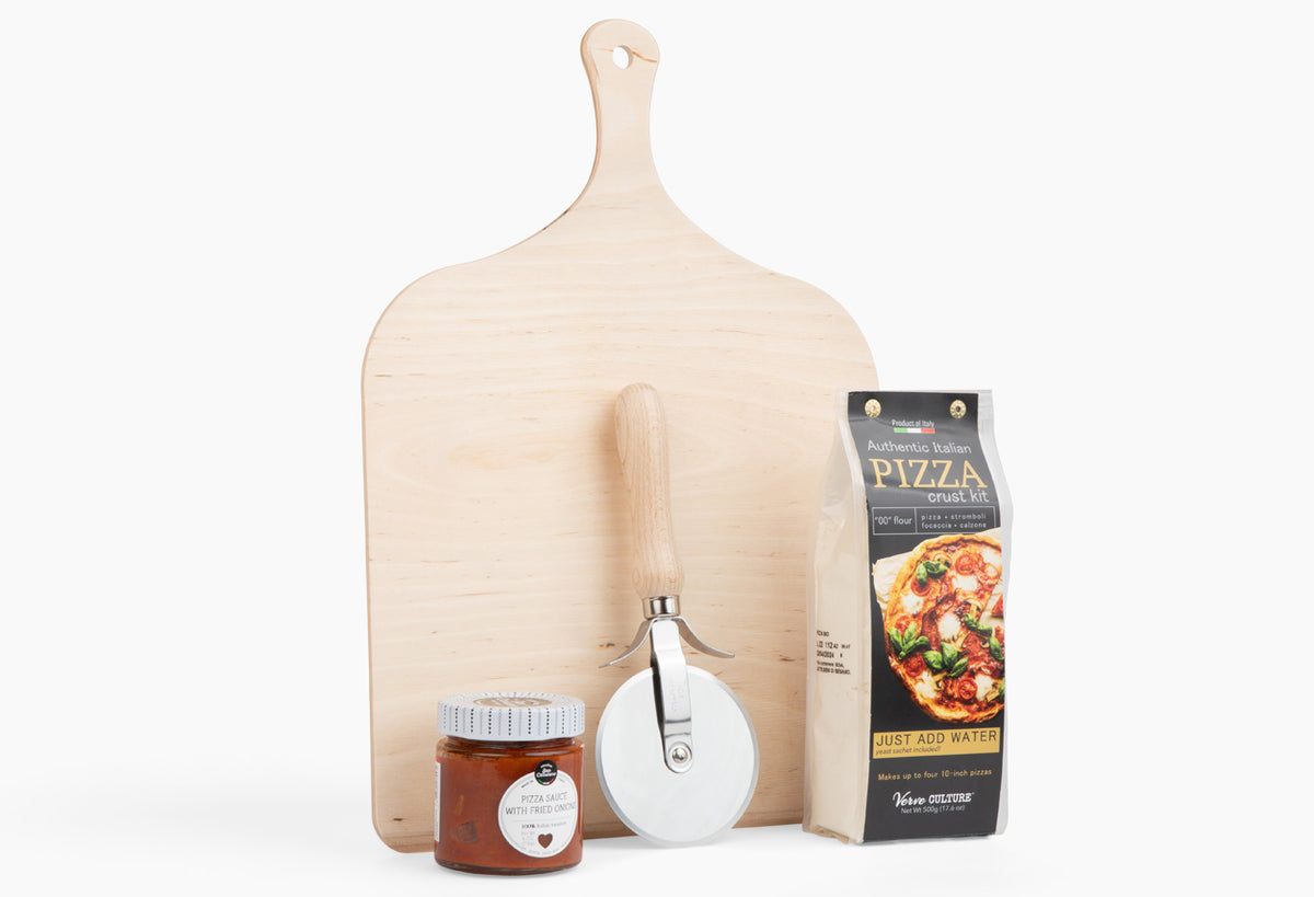 Wooden pizza peel, pizza cutter wheel, jar of sauce, and boxed pizza crust mix arranged on white background.