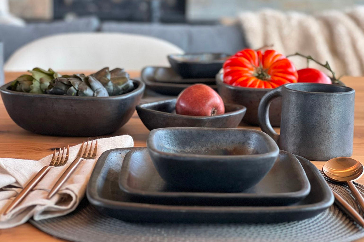 Dark grey handmade pottery dinner plate with rustic textured surface, styled in table setting with matching dinnerware.