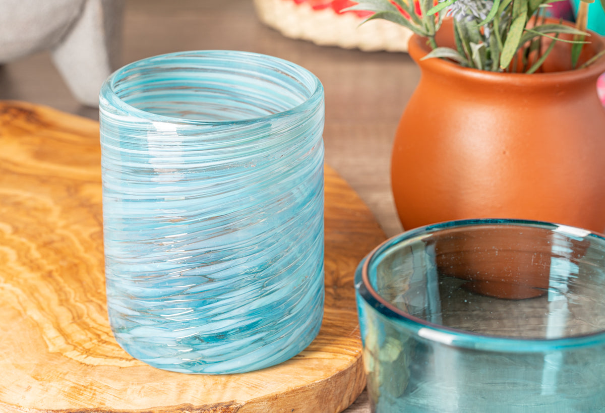 Turquoise handblown glass with swirled pattern, cylindrical shape, displayed on wooden surface.