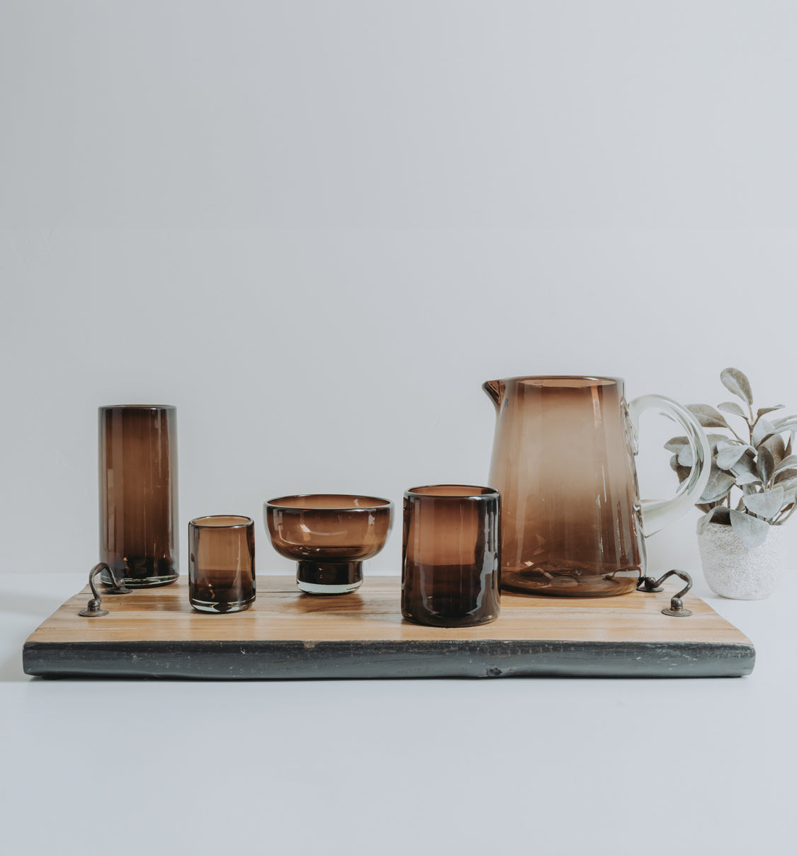 Four tamarind-colored handblown glasses with varying heights and shapes, displaying gradient amber to dark brown tones.