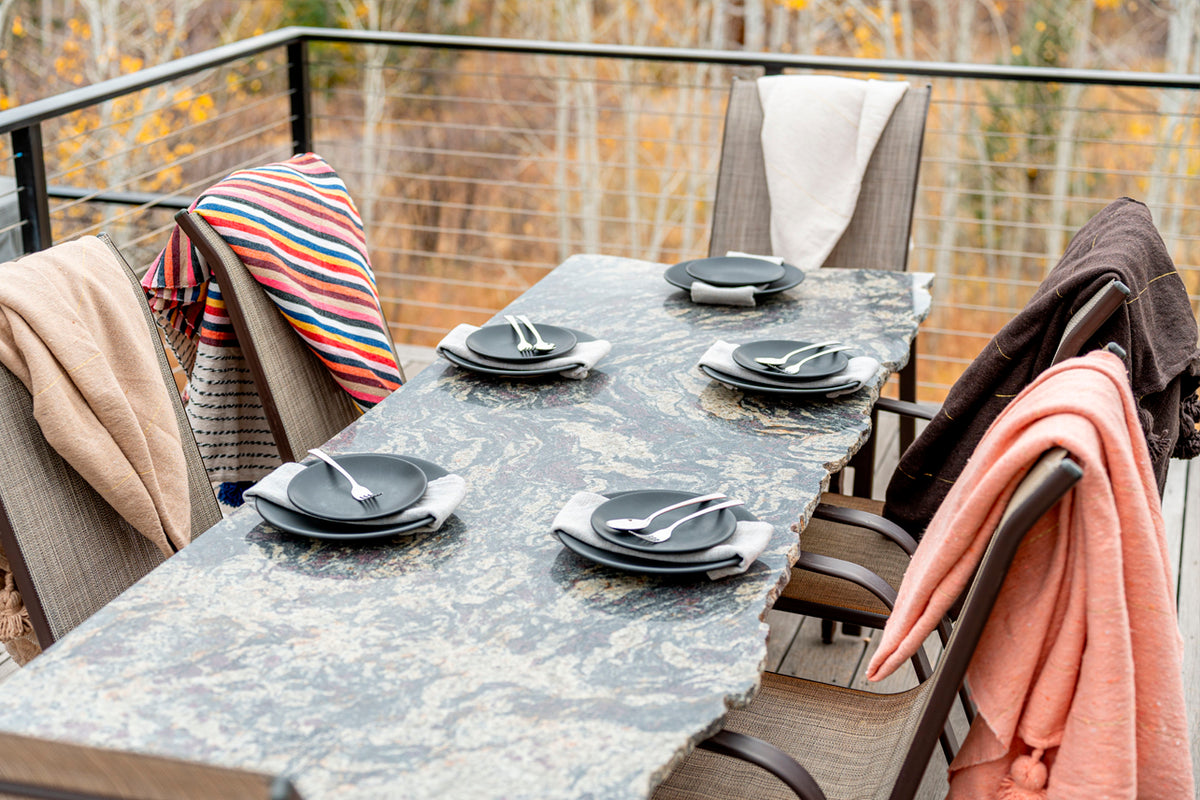 Striped blankets with tassels draped over outdoor dining chairs in various colors including red, blue, and coral.