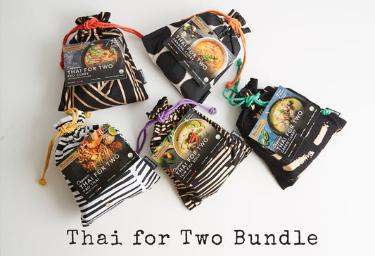 Five black pouches with zebra stripe patterns and colored drawstrings containing Thai curry meal kits.