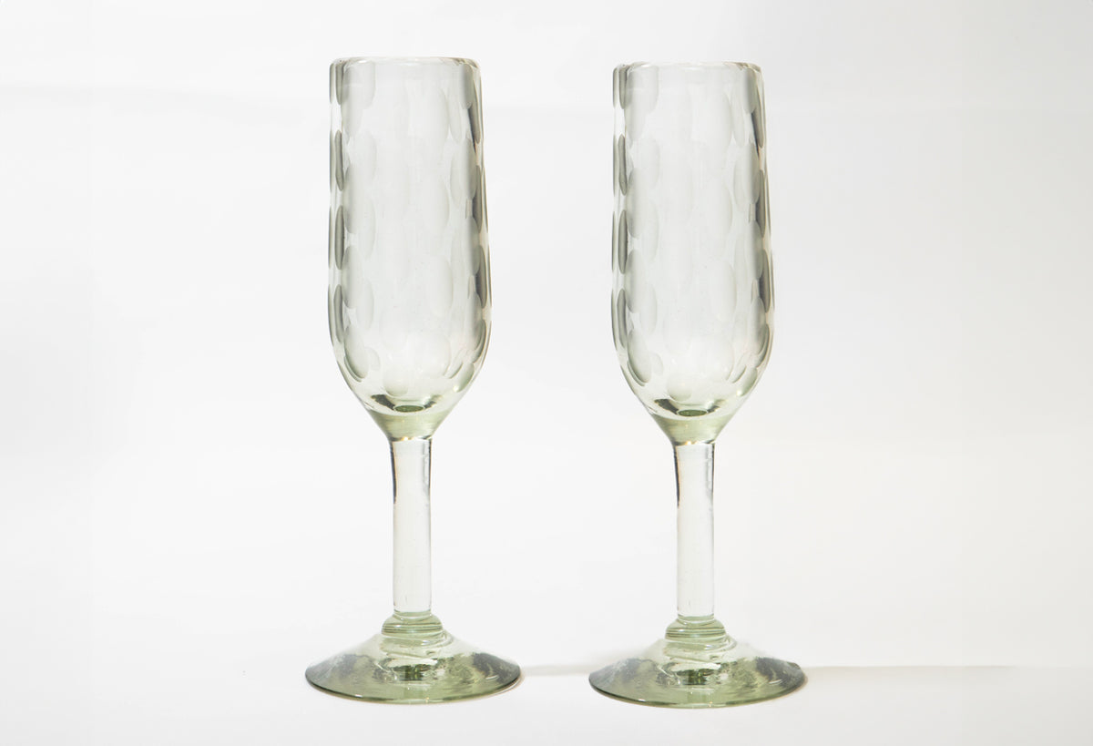Two clear champagne flutes with etched vertical patterns and green-tinted bases.