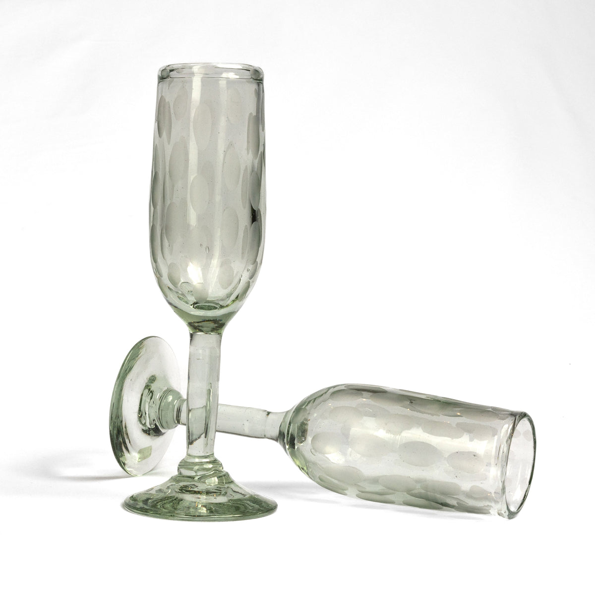 Two clear glass champagne flutes with etched surface patterns and rounded bases on white background.