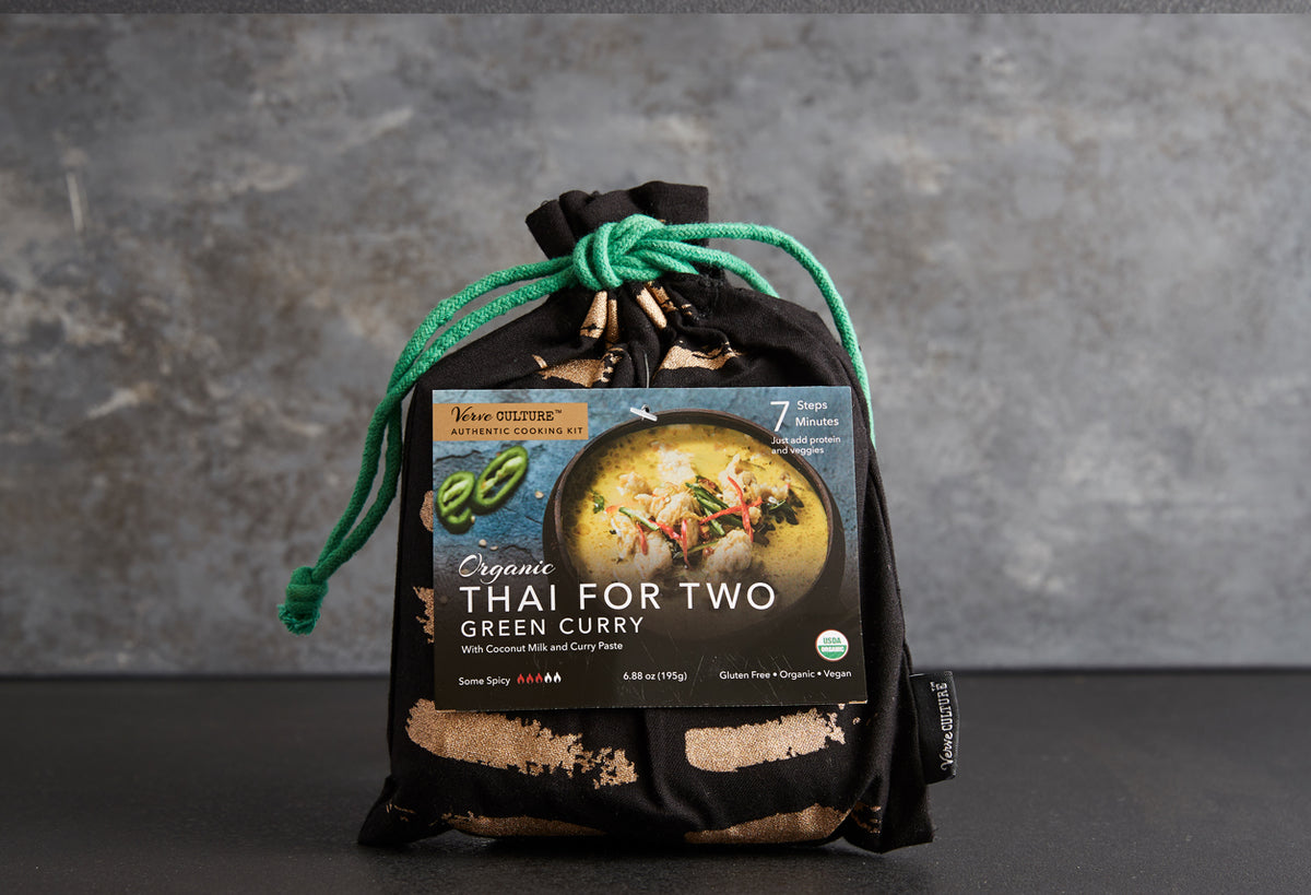 Black cloth bundle tied with green cord containing Thai green curry cooking kit with coconut milk and curry paste packet visi