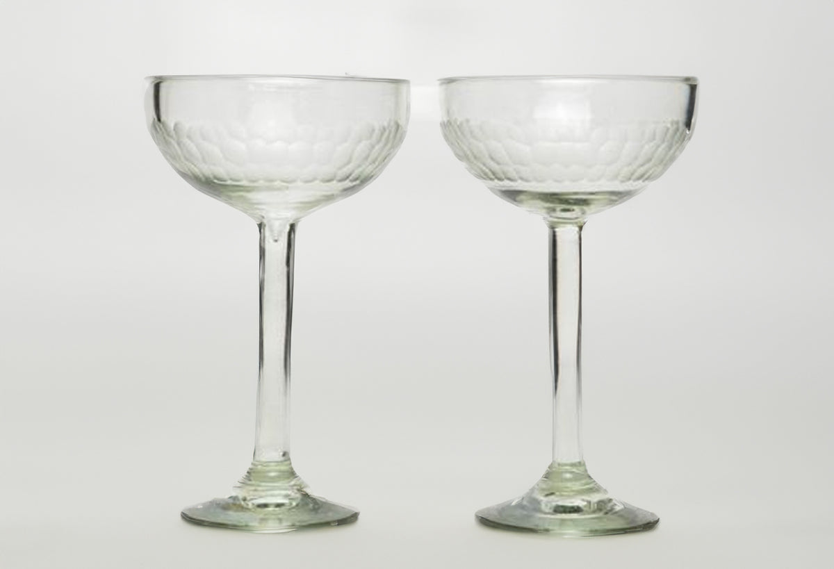 Two clear glass cocktail glasses with etched bowl design and long stems on pedestal bases.