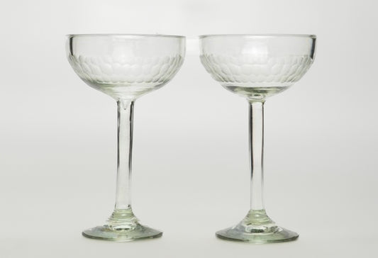 Two clear glass cocktail glasses with etched bowl design and long stems on pedestal bases.