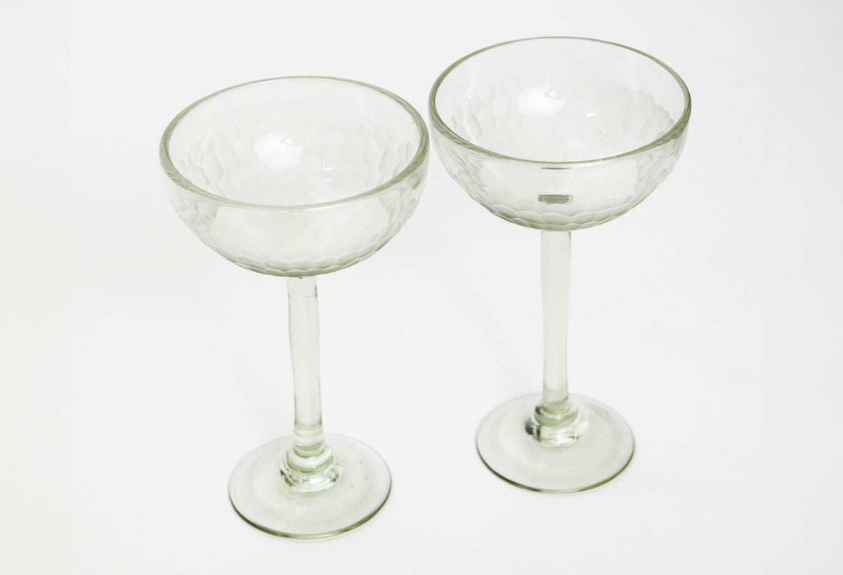 Two clear glass cocktail glasses with etched detailing, long stems, and wide bowls on rounded bases.