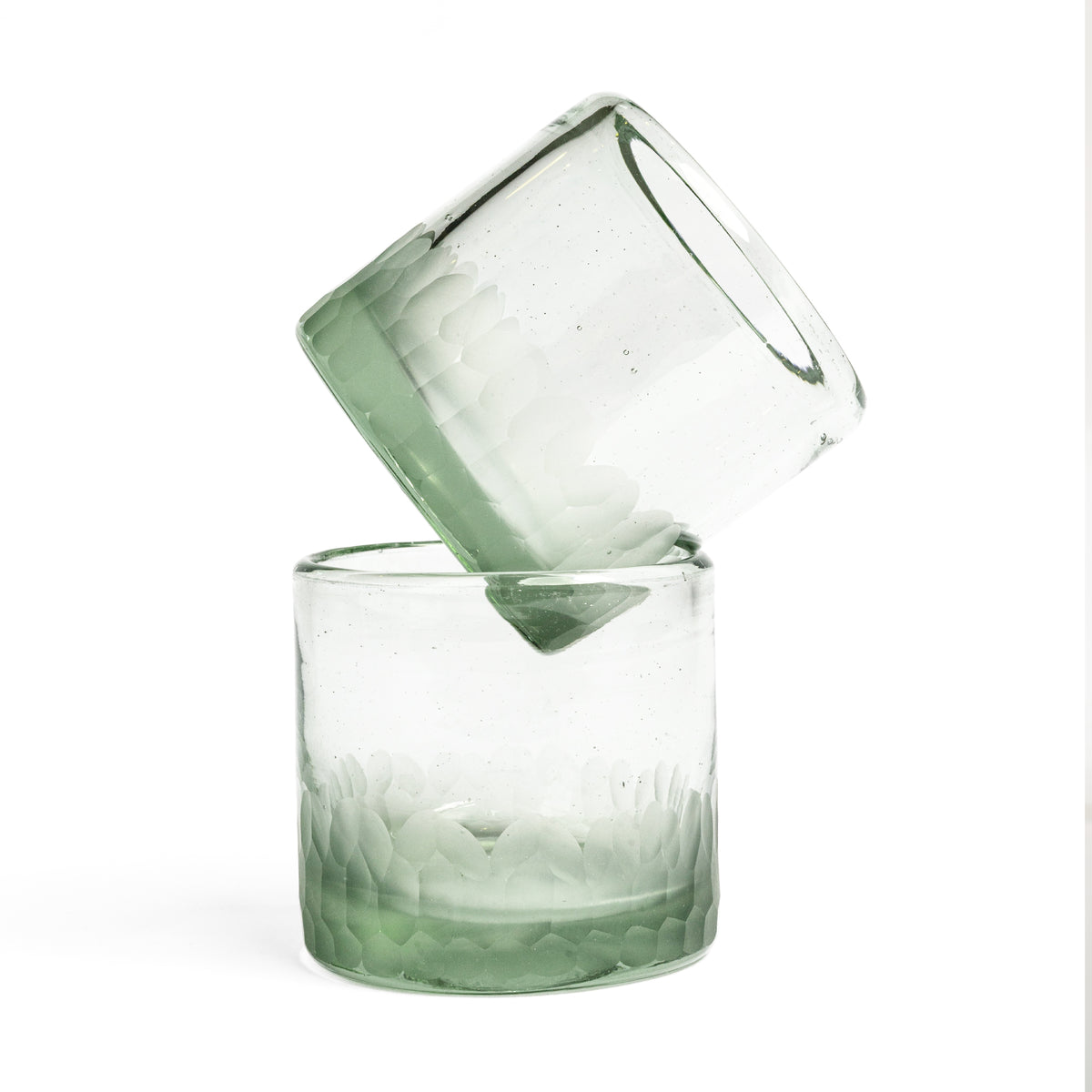 Two clear rocks glasses with green-tinted bases and etched geometric patterns stacked together.