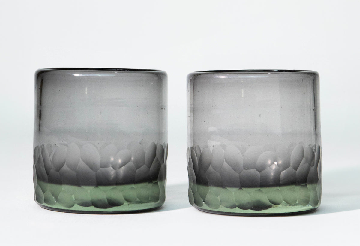 Two clear rocks glasses with etched leaf patterns in gray and green tones around the lower portion.
