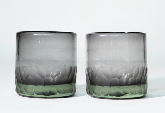 Two clear rocks glasses with etched leaf patterns in gray and green tones around the lower portion.