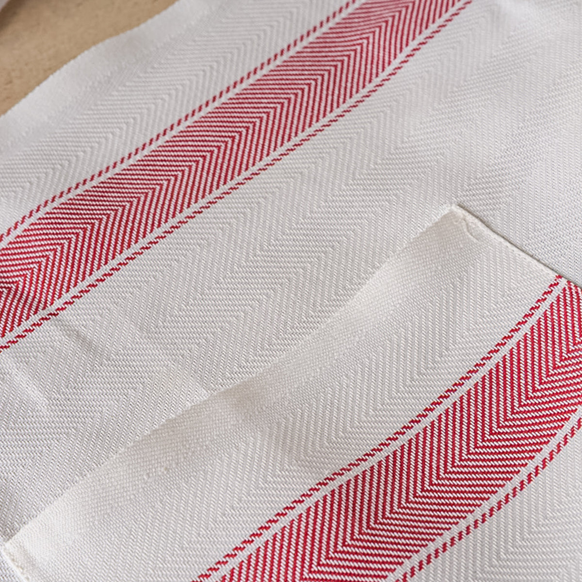White linen apron with red diagonal striped trim and herringbone weave pattern.