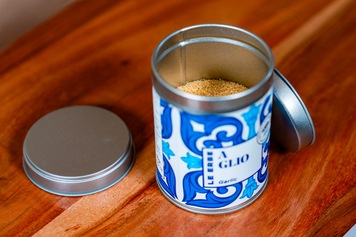 Garlic spice in decorative blue and white tin container with metal lid on wooden surface.