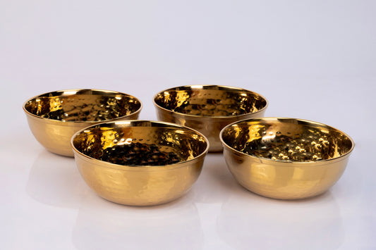 Four gold-toned stainless steel bowls with hammered texture interior surface arranged on white background.