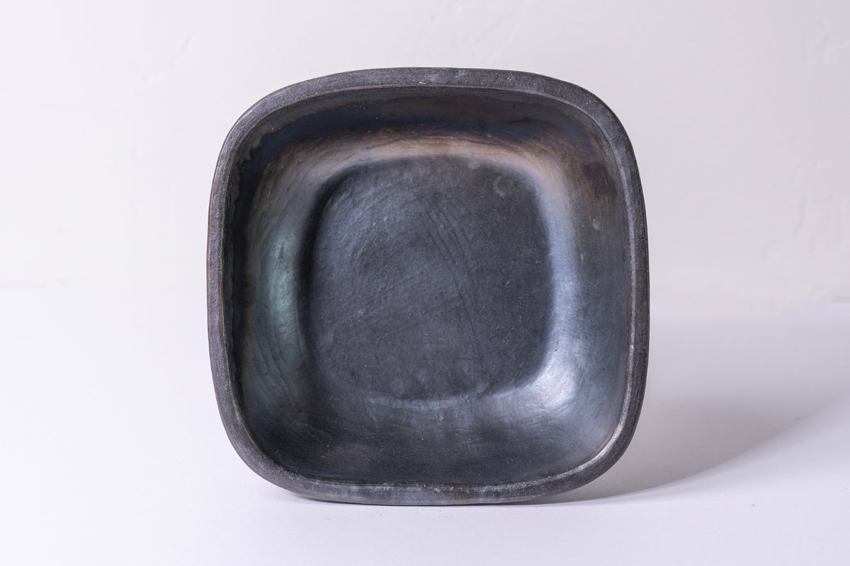 Dark gray square pottery bowl with rounded corners and smooth interior surface.