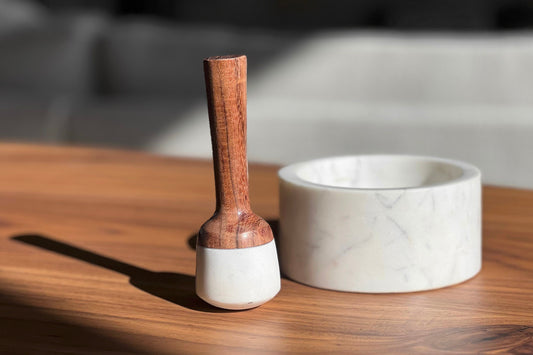 White marble mortar with wooden pestle featuring a marble head and wooden handle.