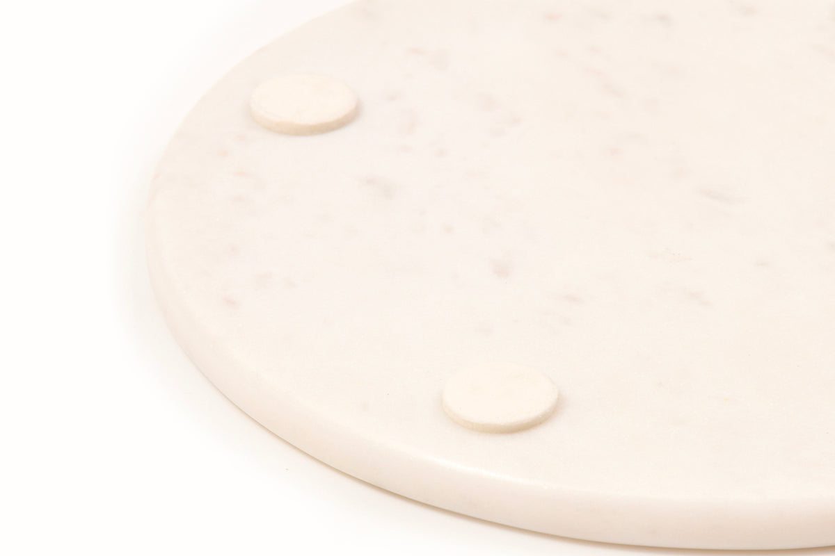 White marble circular board with two ceramic feet on the underside.