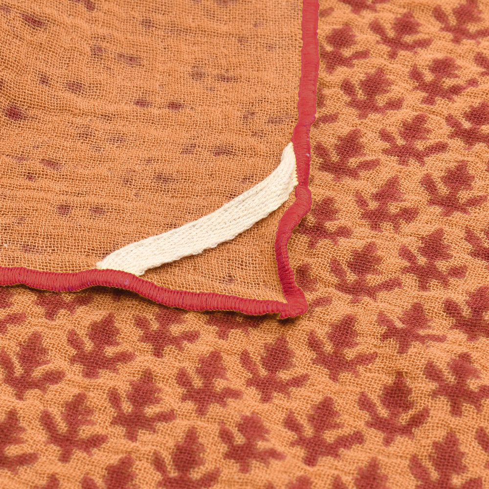Punjabi block print napkins with red and gold geometric pattern and red binding edge detail.