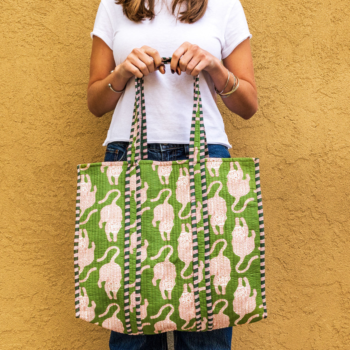 Green quilted tote bag with white cat silhouettes and black checkered stripe handles.