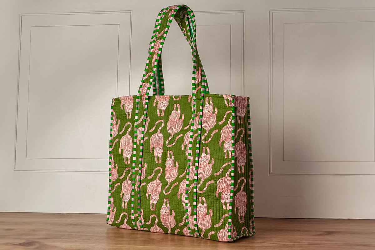 Quilted tote bag with green background, pink cat silhouettes, and matching patterned handles.
