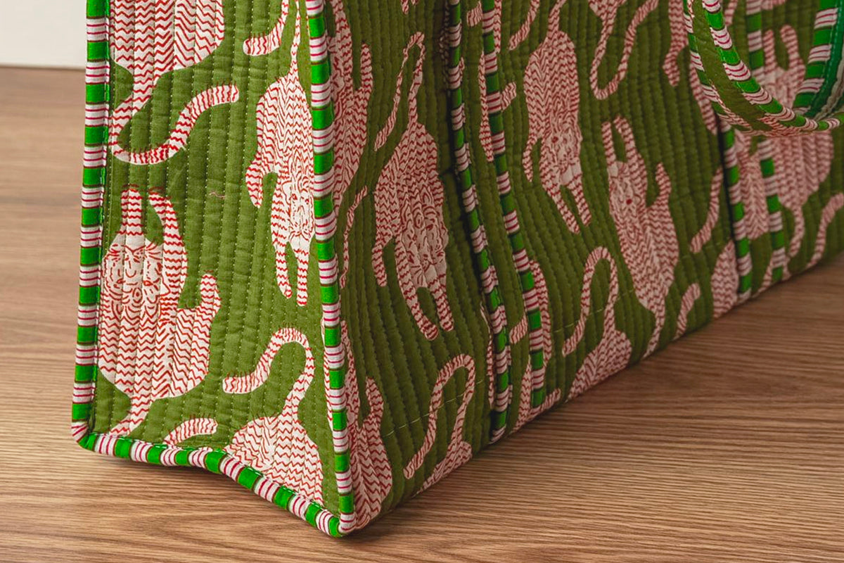 Quilted tote bags with green and pink cat-shaped pattern and striped handles on wooden surface.