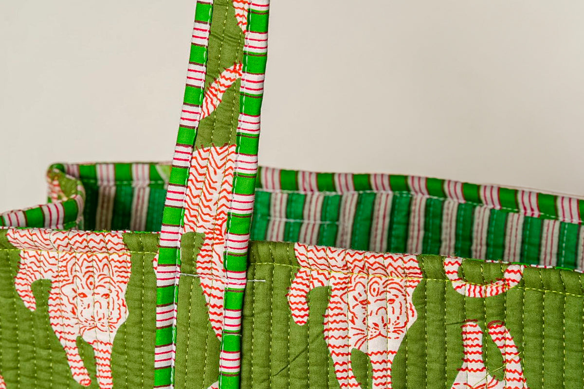 Quilted tote bag with green background and red cat silhouettes, featuring striped handles in green, pink, and white.