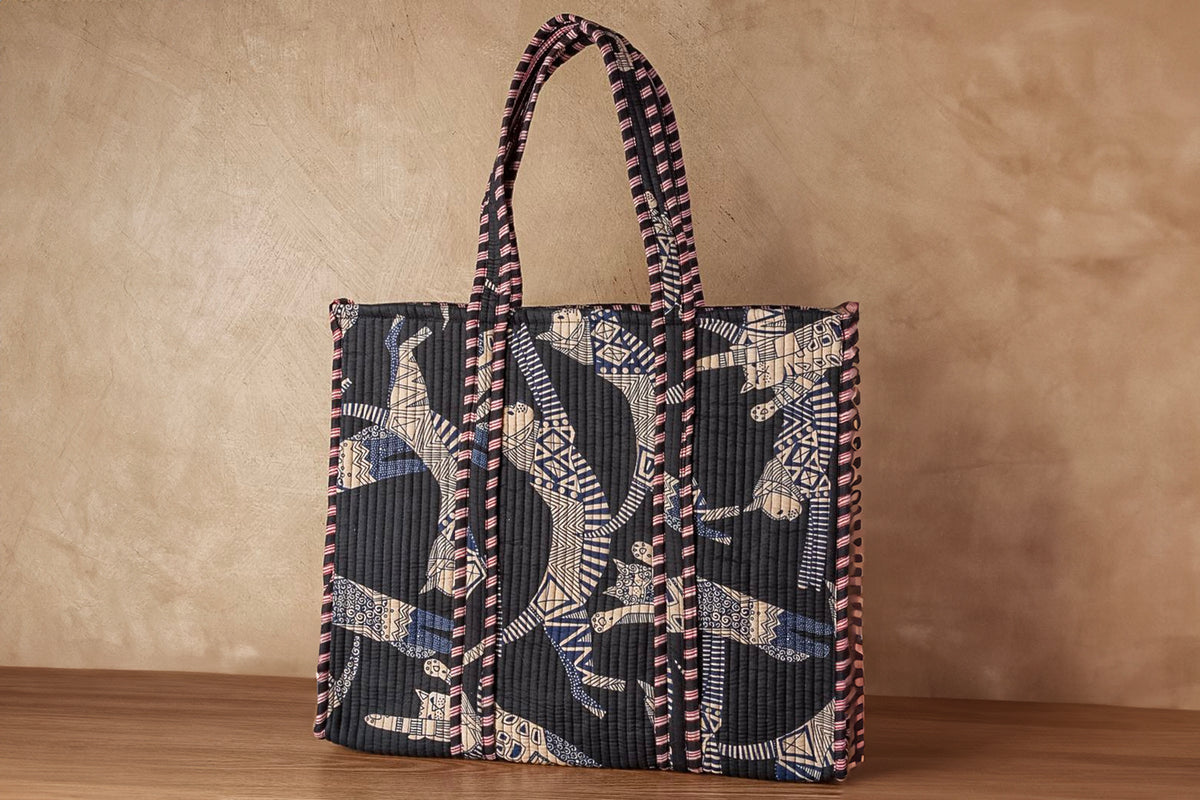 Quilted tote bag with cat face design in black, cream, and blue with checkered handles.