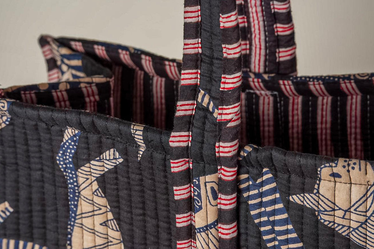 Quilted tote bags with cat face designs in blue, red, and cream stripes on black fabric.