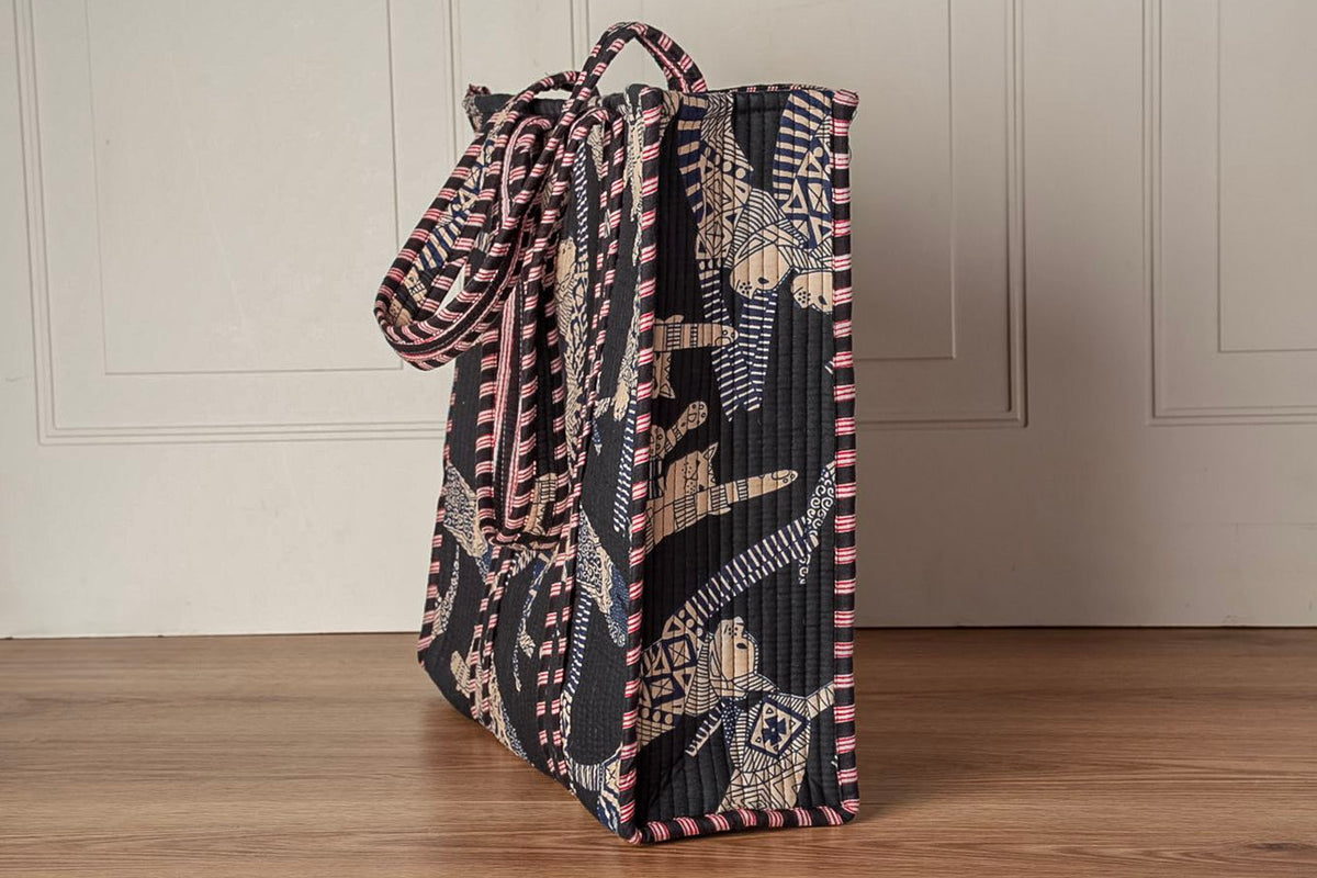 Quilted tote bag with cat motif in black, pink, and cream patchwork patterns and matching handles.