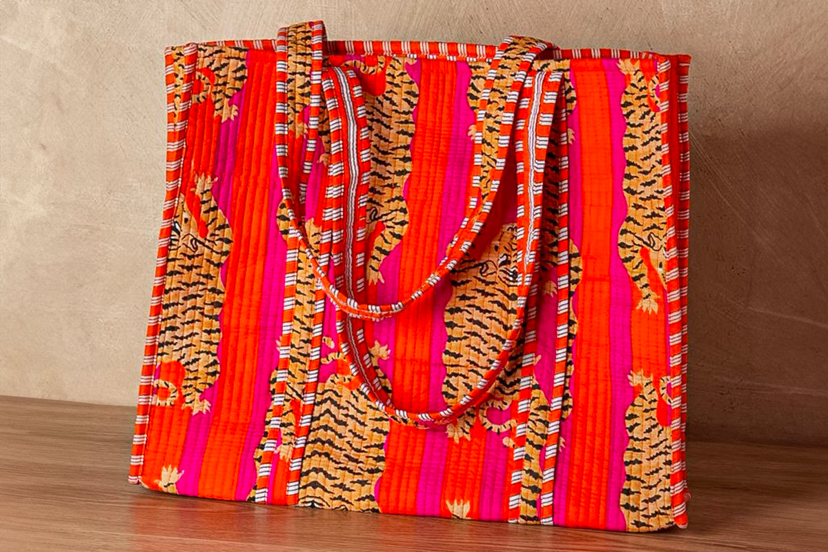 Red and orange quilted tote bag with tiger stripe and geometric patterned fabric, featuring dual fabric handles.