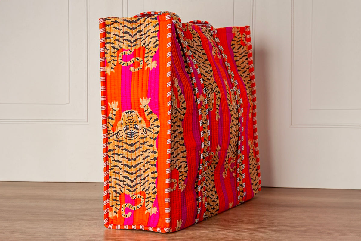 Two quilted totes with tiger stripe and floral patterns in orange, pink, and red with gold embroidered details.