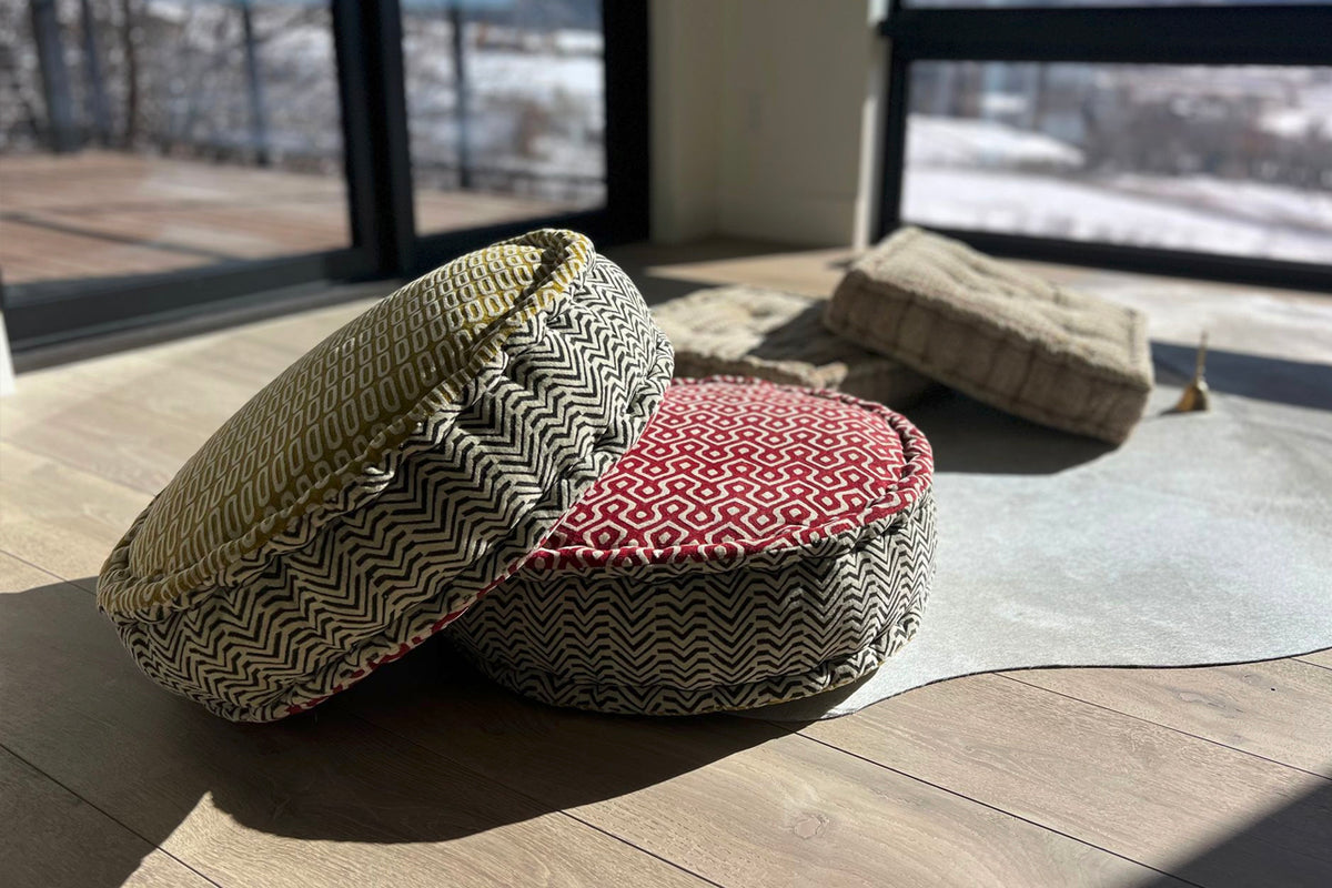 Round meditation cushion with geometric block print patterns in cream and red on both sides.