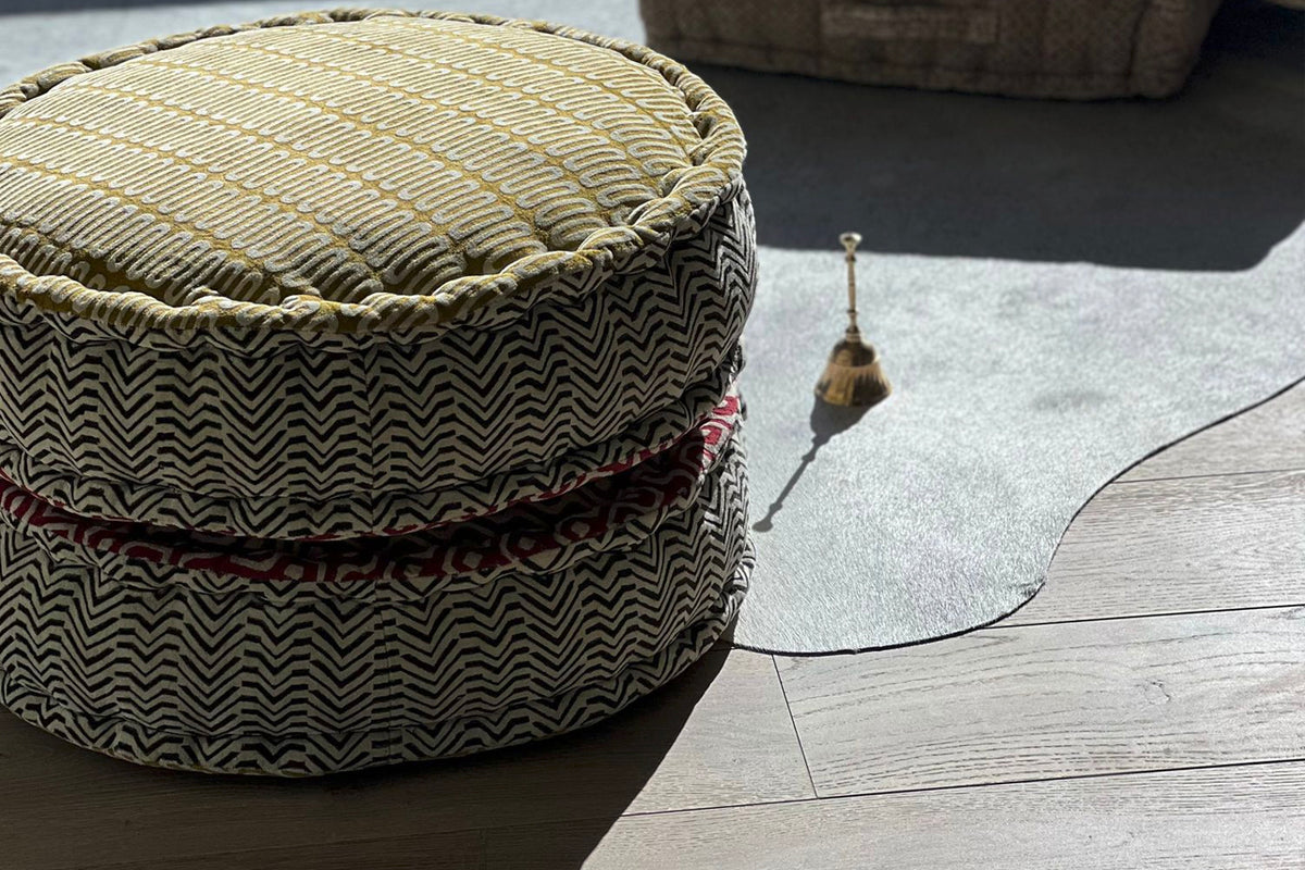 Round meditation cushion with geometric block print pattern in cream and black, shown from side view.