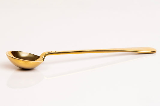 Gold-colored serving spoon with a round bowl and long, slender handle.
