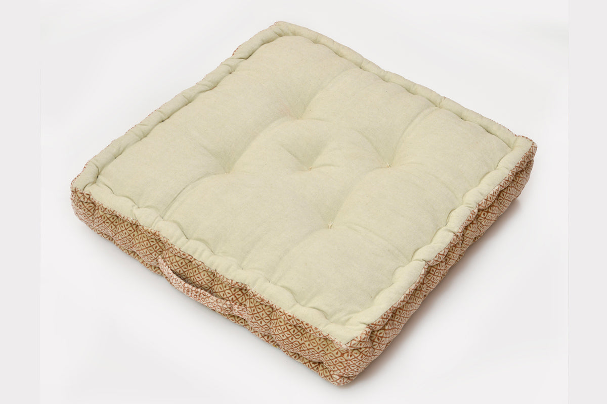 Square meditation cushion with cream quilted top and textured tan block print sides.
