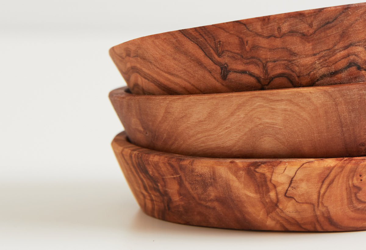 Three stacked wooden bowls in varying shades of olivewood with natural grain patterns.